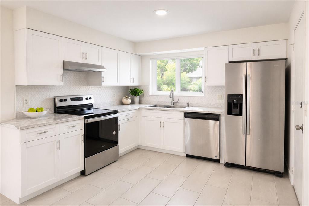 10849 Wheaton Court Orlando, FL 32821 - Photo 6 of 16 a kitchen with white cabinets stainless steel appliances and window