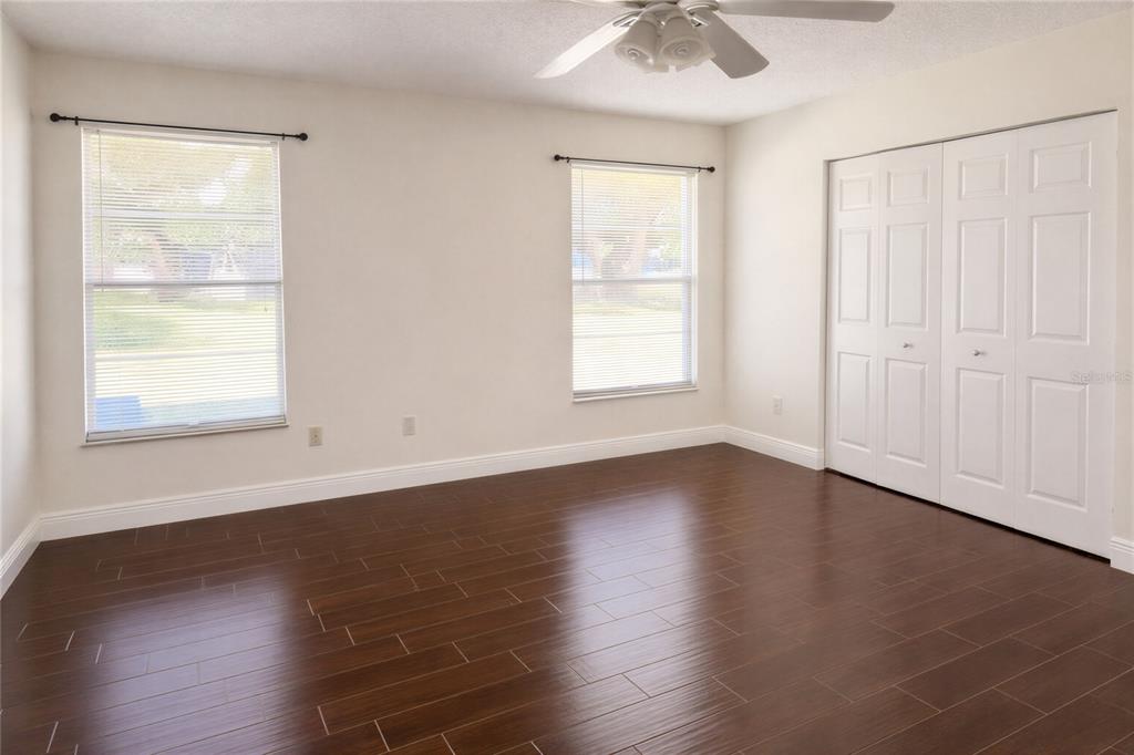10849 Wheaton Court Orlando, FL 32821 - Photo 10 of 16 an empty room with wooden floor chandelier fan and windows