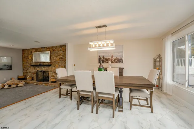 a kitchen with stainless steel appliances kitchen island granite countertop a refrigerator a stove a dining table and chairs with wooden floor