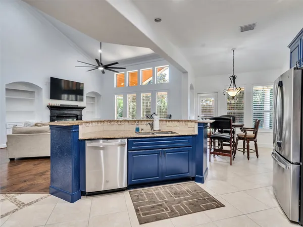 a kitchen with stainless steel appliances granite countertop a stove top oven a sink dishwasher a dining table and chairs with wooden floor