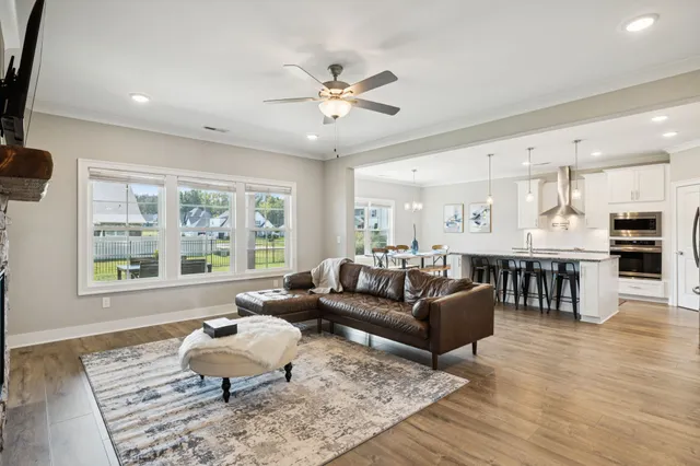 a kitchen with stainless steel appliances granite countertop a table chairs wooden floors and a view of living room