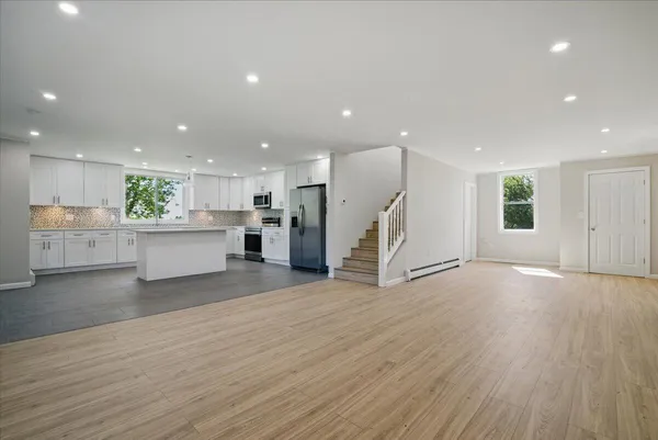 an empty room with wooden floor ceiling fan and windows