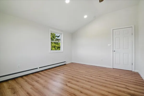 a view of an empty room with wooden floor and a window