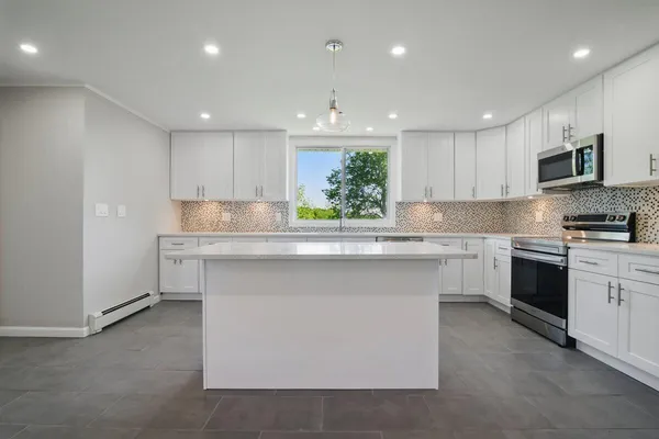 a kitchen with stainless steel appliances kitchen island granite countertop a stove top oven a sink and a refrigerator