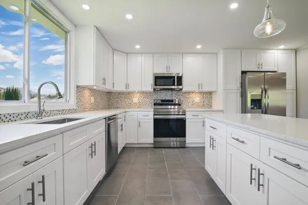 a large kitchen with stainless steel appliances a large counter top a stove and a refrigerator