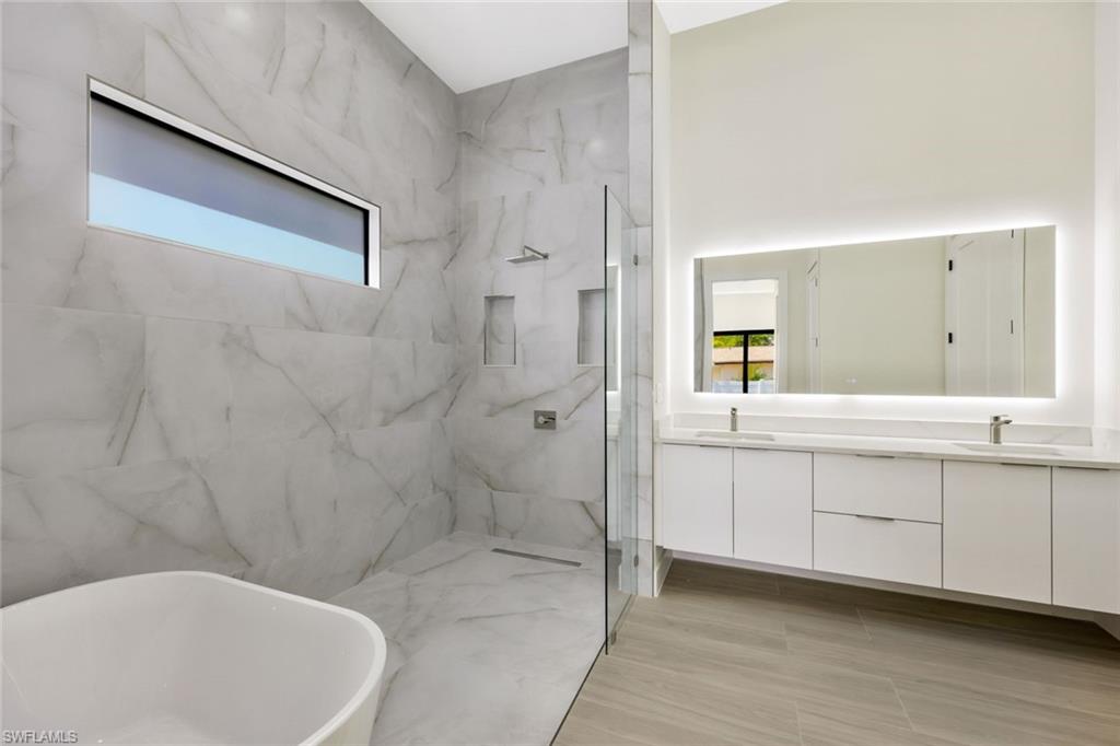 1297 Trail Terrace Drive Naples, FL 34103 - Photo 18 of 29 a bathroom with a bathtub a sink a toilet and a mirror
