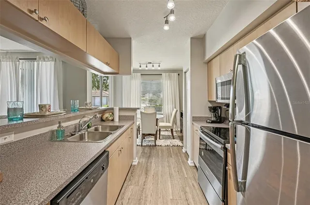 a kitchen with a sink appliances wooden floor and a window