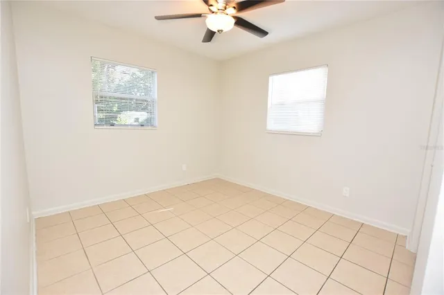an empty room with windows and ceiling fan