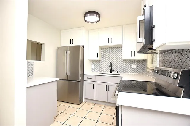 a kitchen with a sink a refrigerator and cabinets