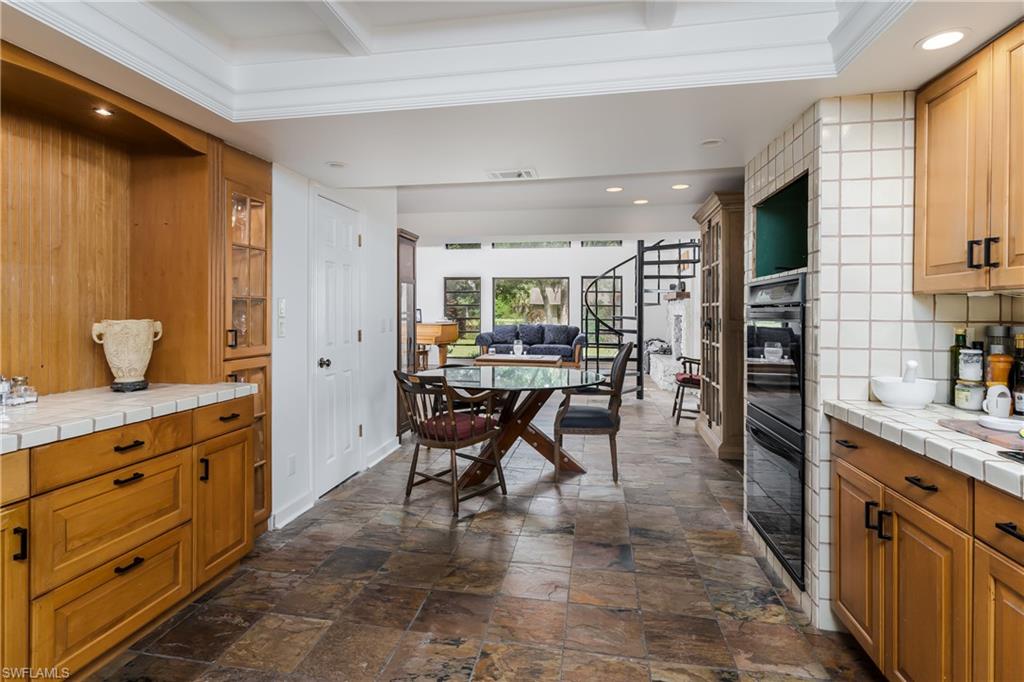 3301 31st Avenue Southwest Naples, FL 34117 - Photo 7 of 22 a kitchen with stainless steel appliances kitchen island granite countertop a table chairs sink and cabinets