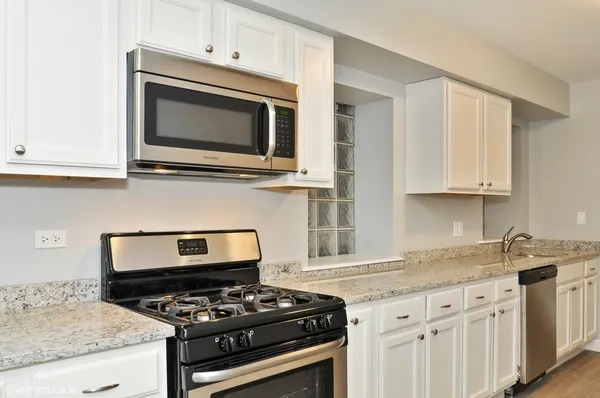 a kitchen with granite countertop white cabinets stainless steel appliances and a sink