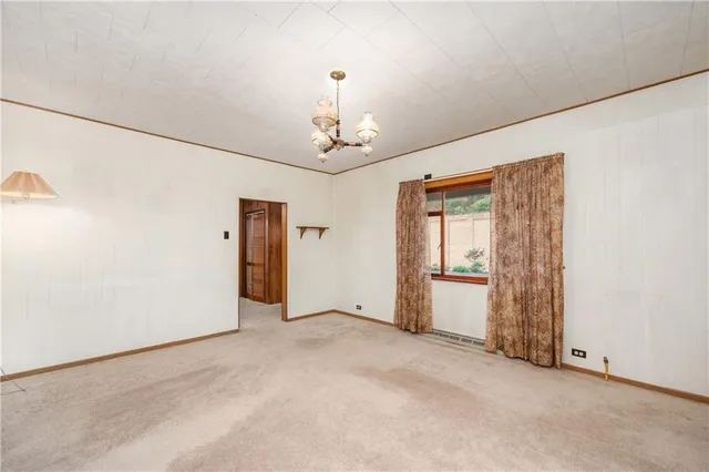 an empty room with chandelier fan and windows