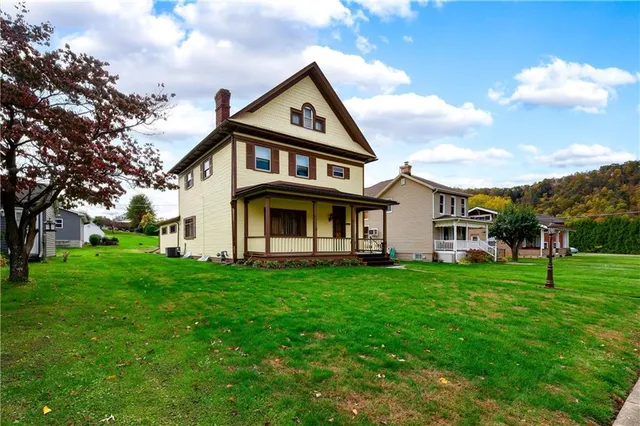 a view of a white house with a big yard and large trees