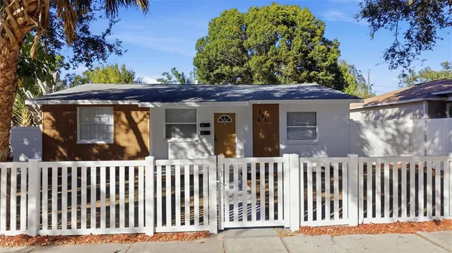 a view of a house with a small yard and large trees