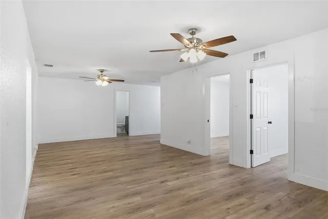 a view of empty room with wooden floor and ceiling fan