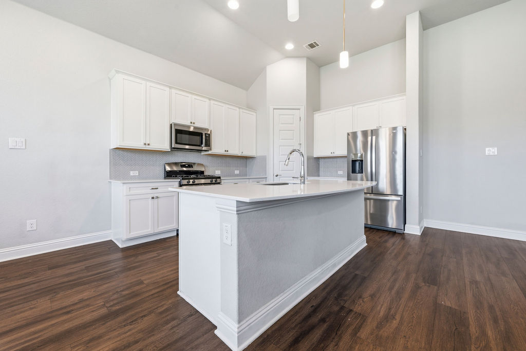2032 Base Burner Path Leander, TX 78641 - Photo 8 of 34 Kitchen featuring a central island, white cabinetry, stainless steel appliances, wood-finish flooring, and recessed lighting