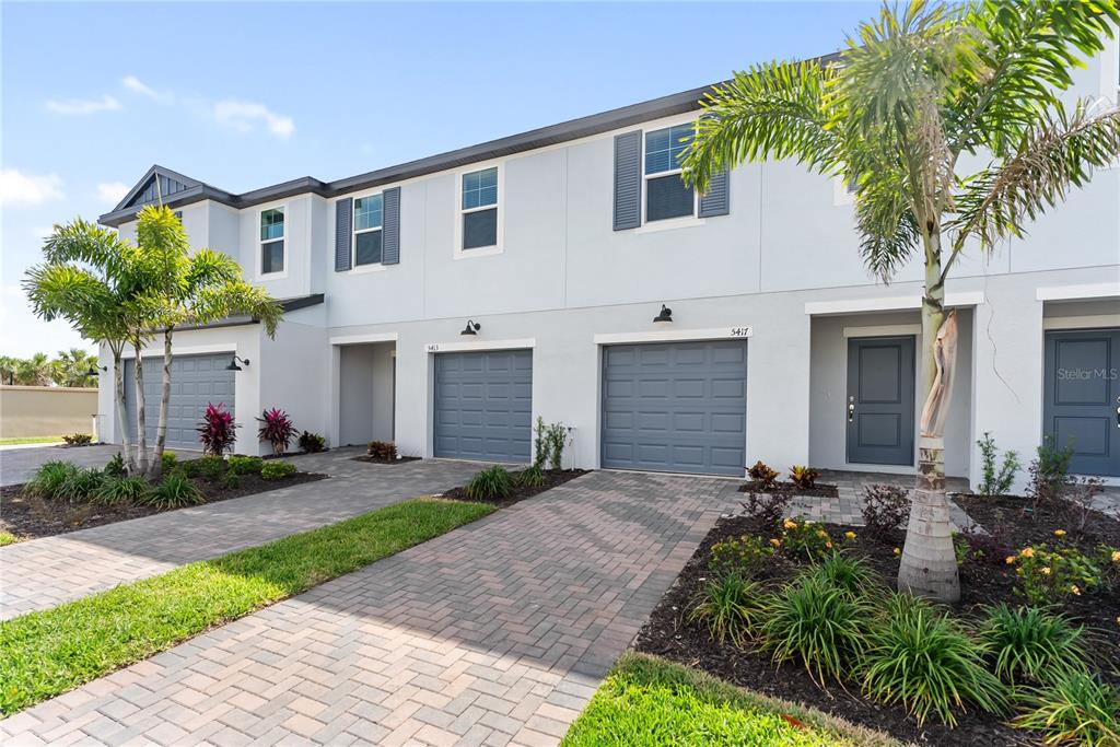 a front view of a house with a yard and potted plants