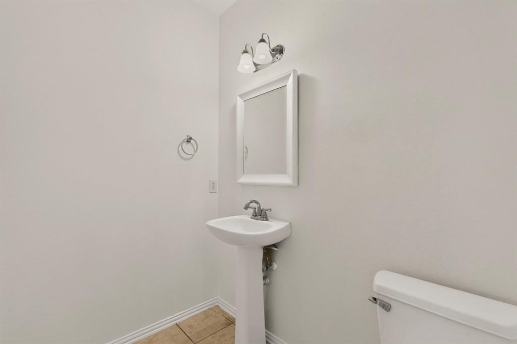 14908 Riverside Drive Little Elm, TX 75068 - Photo 34 of 40 Pedestal sink, wall-mounted mirror, ceramic tile flooring, and wall-mounted vanity lighting