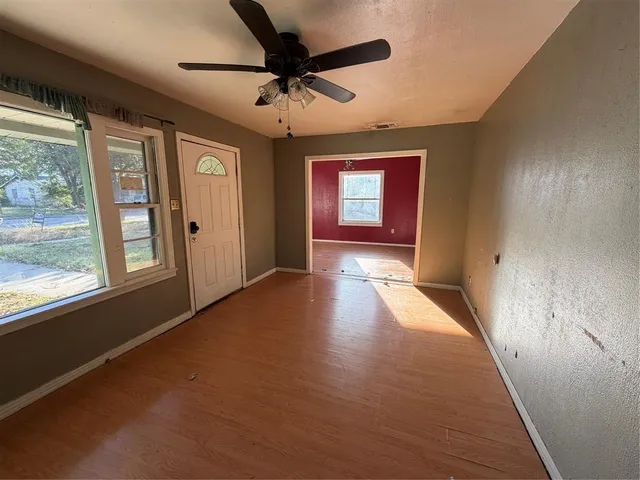 an empty room with windows and fan