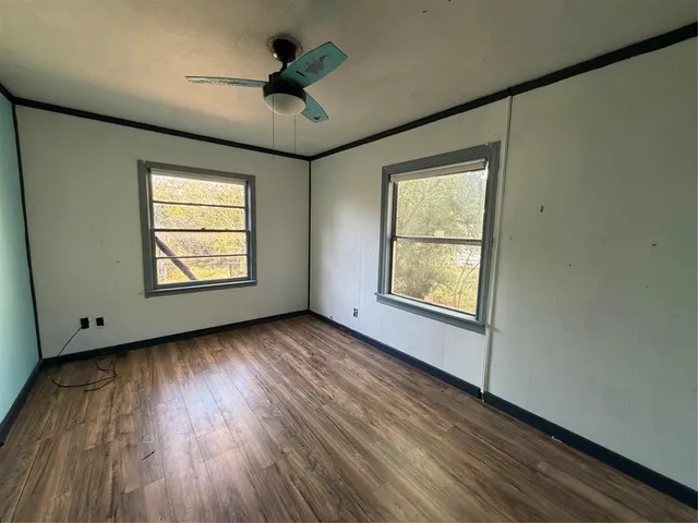 an empty room with wooden floor chandelier and windows