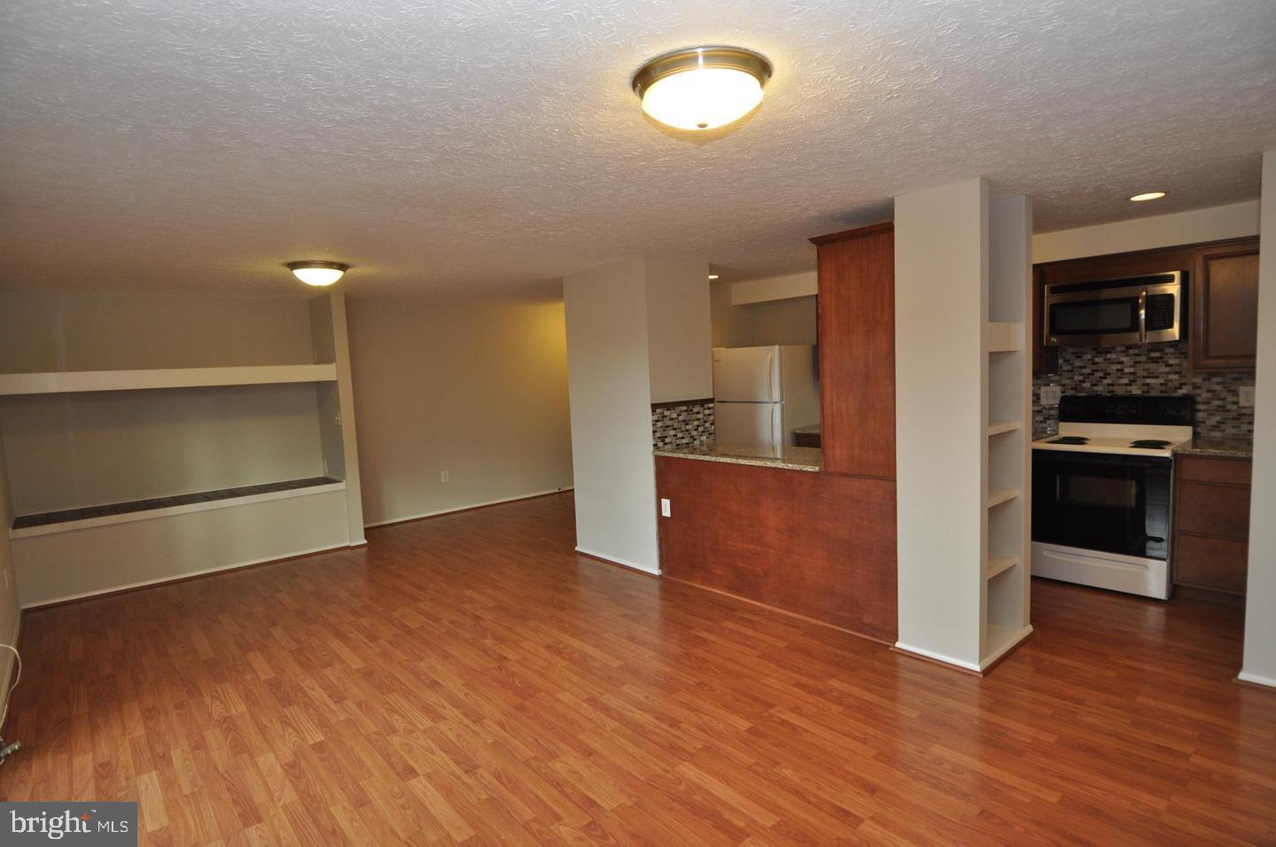 19609 Gunners Branch Road, Unit F Germantown, MD 20876 - Photo 3 of 18 an empty room with wooden floor kitchen view and windows