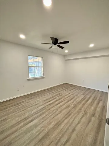 an empty room with wooden floor fan and windows