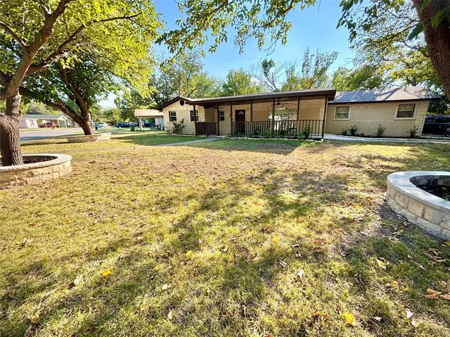 a view of house with yard outdoor seating and covered with trees