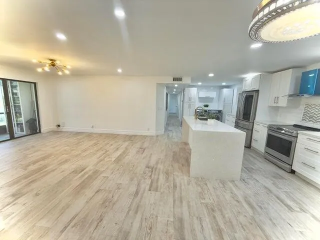 a view of a kitchen with kitchen island a sink wooden floor and a living room view