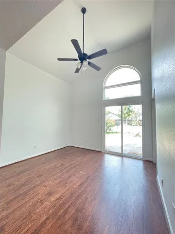 an empty room with wooden floor fireplace and windows