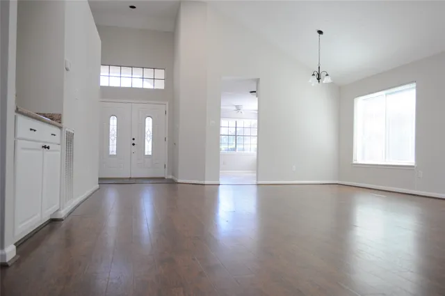 an empty room with wooden floor fan and windows