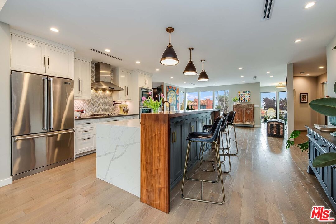 7407 Earldom Avenue Playa del Rey, CA 90293 - Photo 14 of 56 a kitchen with stainless steel appliances granite countertop a refrigerator a stove a sink a dining table and chairs with wooden floor