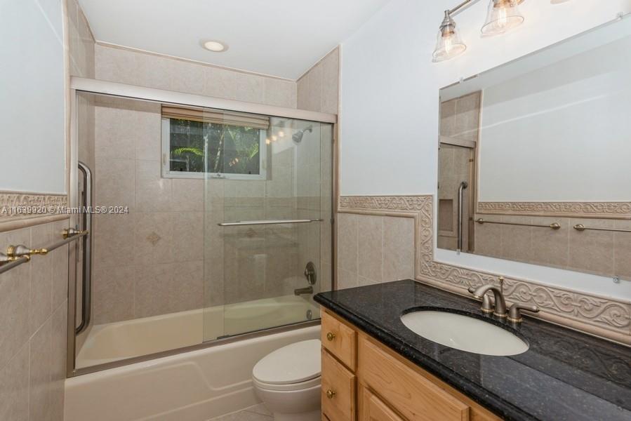 7772 Southwest 106th Terrace Pinecrest, FL 33156 - Photo 9 of 24 a bathroom with a granite countertop sink toilet mirror and shower