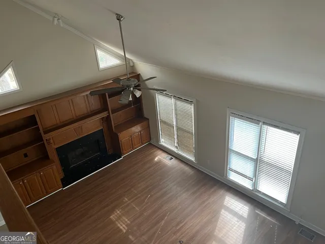 an empty room with wooden floor chandelier fan and windows