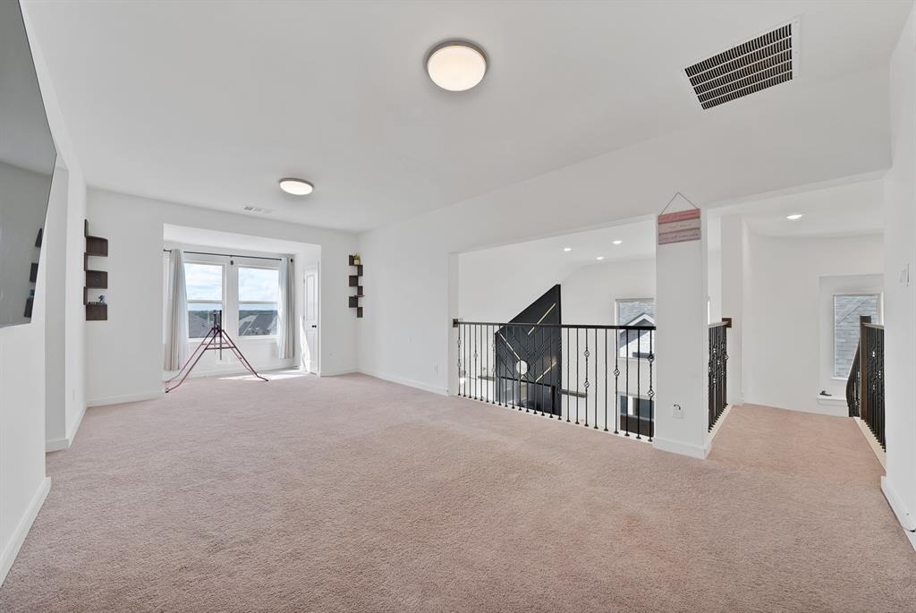 4222 Crown Run Road Midlothian, TX 76065 - Photo 26 of 40 Spacious carpeted room featuring a large window, recessed lighting, and an open railing overlooking the floor below