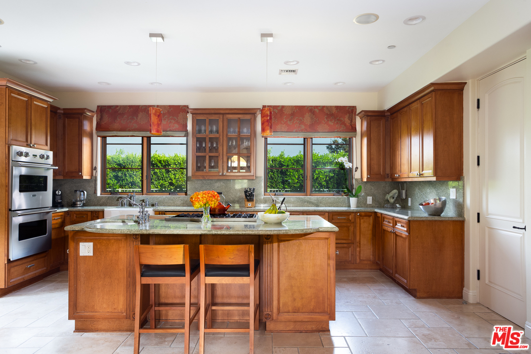 3110 Benedict Canyon Drive Beverly Hills, CA 90210 - Photo 15 of 45 a kitchen with stainless steel appliances granite countertop wooden cabinets a table and chairs