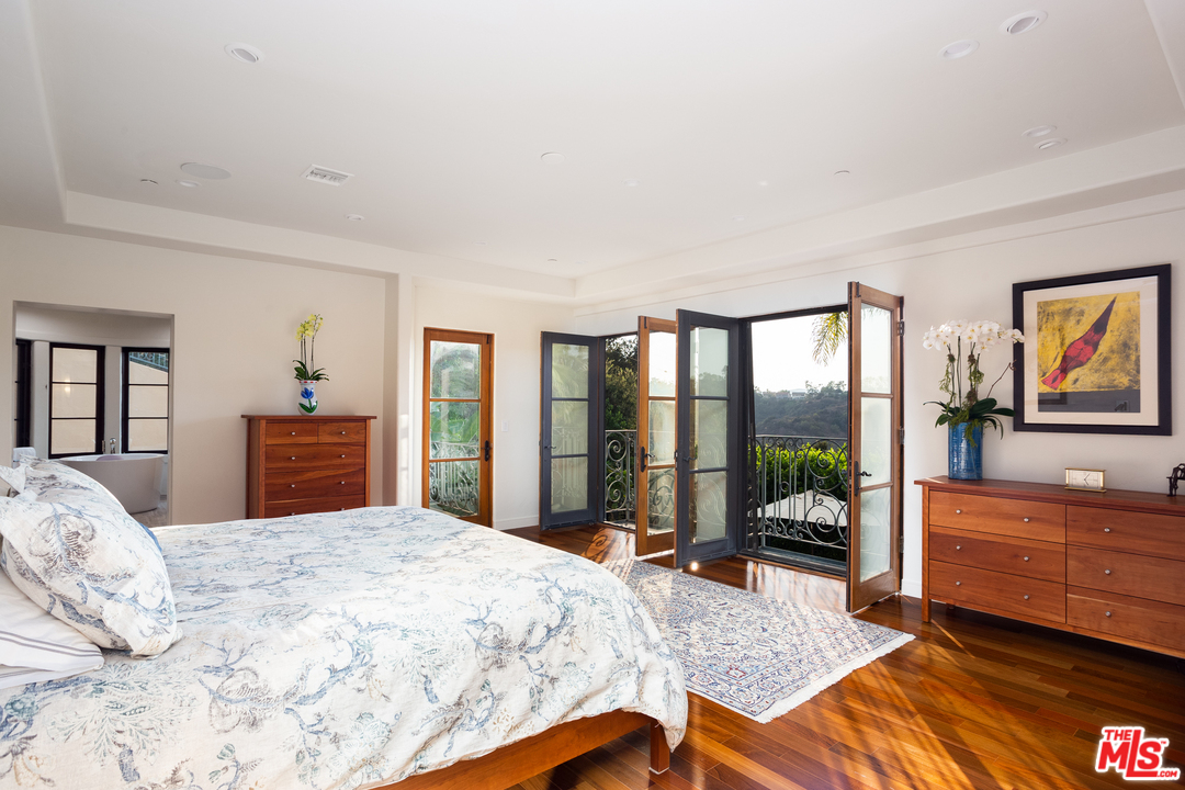 3110 Benedict Canyon Drive Beverly Hills, CA 90210 - Photo 20 of 45 a bedroom with a bed and a large window with balcony view