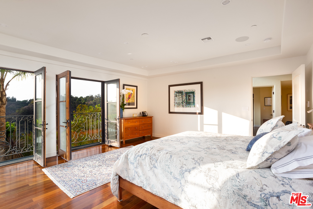 3110 Benedict Canyon Drive Beverly Hills, CA 90210 - Photo 22 of 45 a bedroom with a large bed and a balcony view