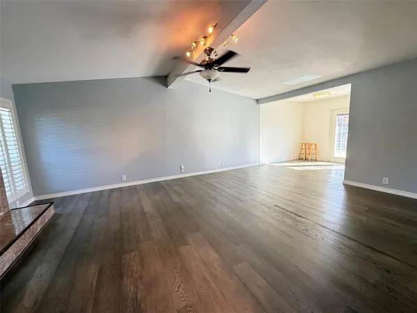 an empty room with wooden floor fan and windows