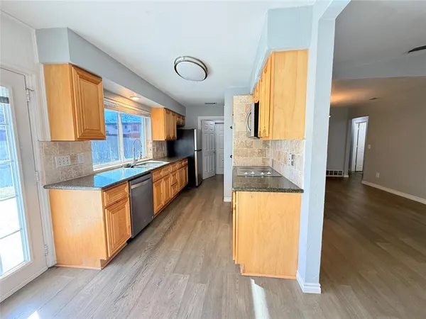 a kitchen with stainless steel appliances granite countertop wooden floors and white cabinets