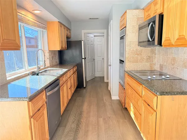 a kitchen with stainless steel appliances granite countertop a sink and a refrigerator