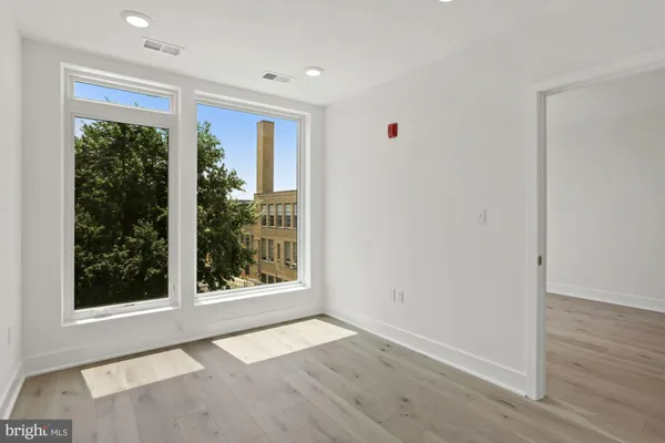 an empty room with wooden floor and windows