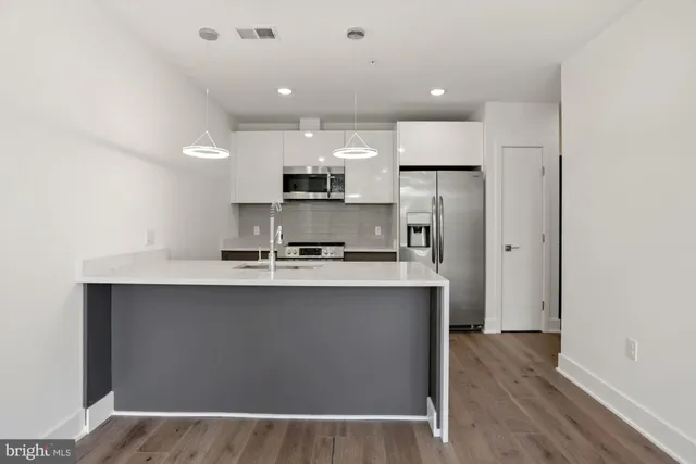 a kitchen with kitchen island a sink stainless steel appliances and cabinets