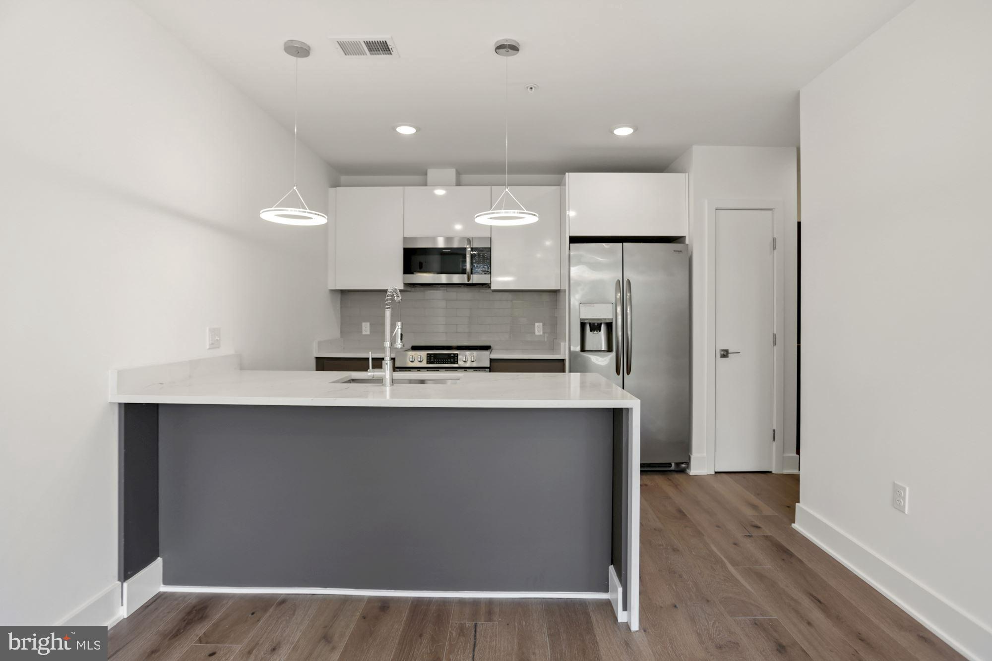 2027 Rhode Island Avenue Northeast, Unit 401 Washington, DC 20018 - Photo 8 of 29 a kitchen with kitchen island a sink stainless steel appliances and cabinets