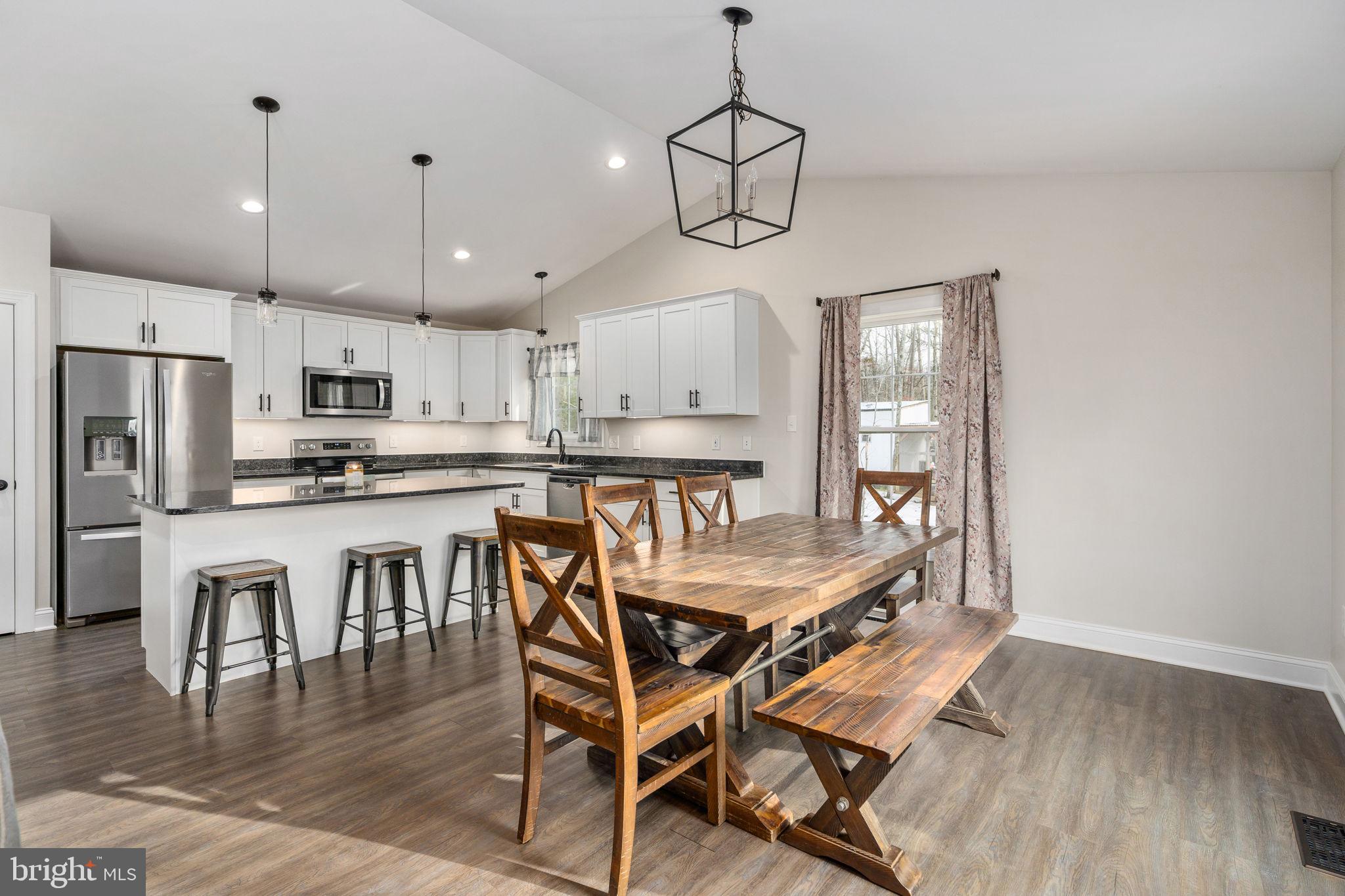 10514 Hart Court Culpeper, VA 22701 - Photo 7 of 34 a dining room with stainless steel appliances kitchen island granite countertop a table chairs and a refrigerator