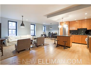 a living room with couches and kitchen view with wooden floor