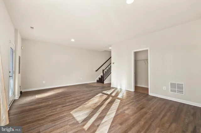 a view of empty room with wooden floor and stairs