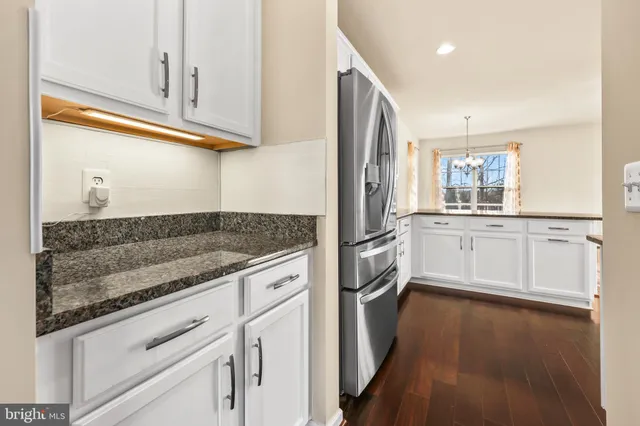 a kitchen with granite countertop a sink cabinets stainless steel appliances and a window