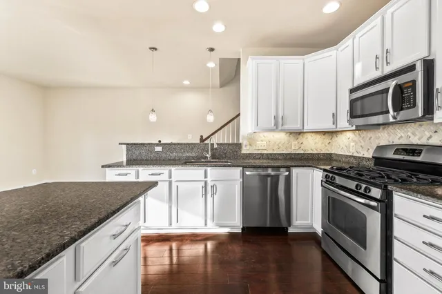 a kitchen with stainless steel appliances granite countertop a stove a sink and a microwave