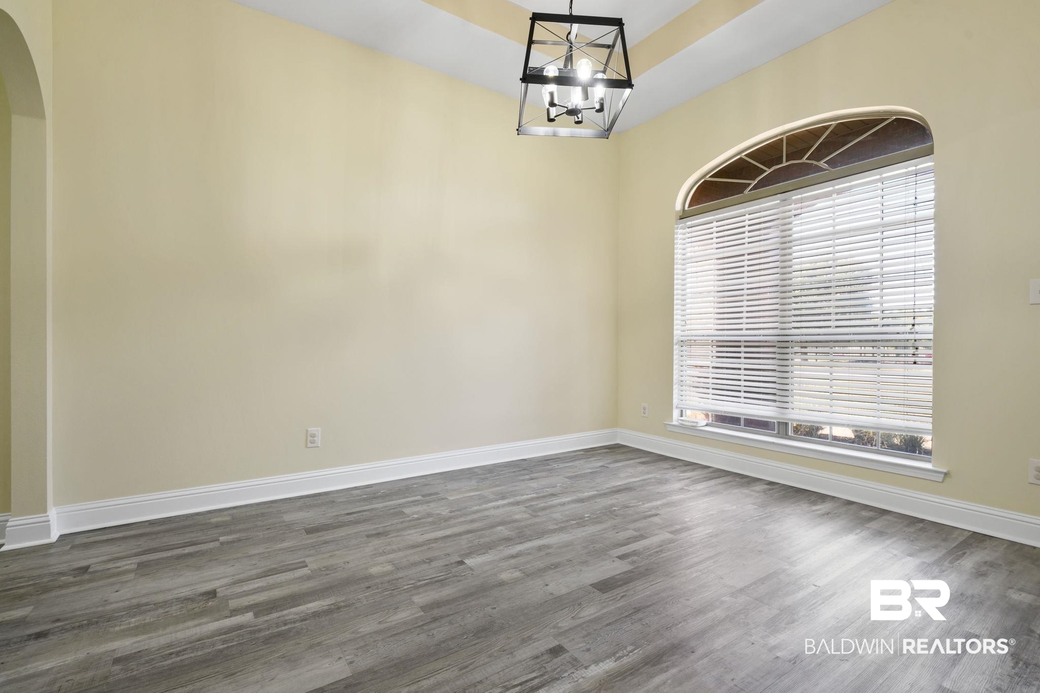 25234 Fairfax Road Daphne, AL 36526 - Photo 11 of 45 Unfurnished dining area with wood finished floors, arched walkways, and a chandelier