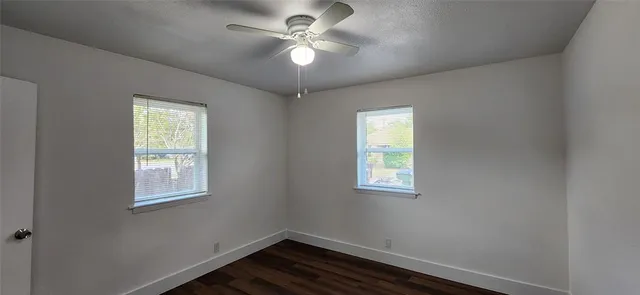 an empty room with windows and fan